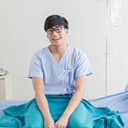 Young man in hospital gown sitting smiling
