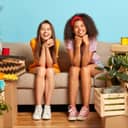 Two smiling young women sitting on a couch