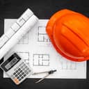 Top view of a construction helmet resting on top of architectural blueprints.