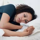 Young woman lying in bed looking at pregnancy test