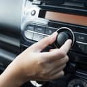 A person turning to knob on the car radio to increase volume