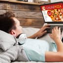 A man laying in bed ordering a pizza online