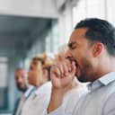 businessman appearing tired and yawning during a meeting or presentation with his team
