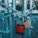 A metal gate locked with a chain and two locks