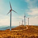 Wind turbines on beautiful sunny summer autumn mountain landsape. Curvy road through mountain Eolic park. Green ecological power energy generation. Wind farm eco field
