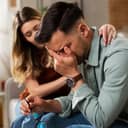 A young man crying while being comforted by a young woman