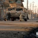 U.S. Army Soldiers attached to Heavy Company, 3rd Squadron, 3rd Armored Cavalry Regiment take cover behind their vehicle after hearing small arms fire in the distance in Mosul, Iraq, Jan. 17, 2008.