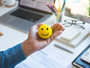 A closeup of a man holding a rubber smiley ball while at his office desk