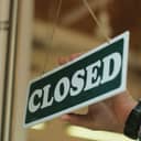 close-up view of a young man's hands flipping a "close" sign in the door of his cafe
