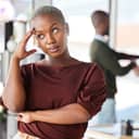irritated businesswoman rolling her eyes in reaction to what's happening behind her back in the office