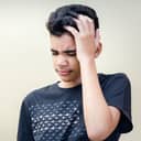 A teenager holding his head with pain on his face
