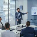 young male businessman presenting results of research on a wall TV displaying data analysis in an office meeting room