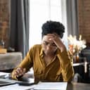 A young female business owner visibly upset and stressed while handling financial documents.