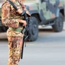 Italian soldier armed with a rifle standing near a military SUV vehicle
