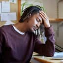 Man with closed eyes resting his head on the arm and table