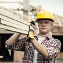 construction worker with safety gear carrying wooden beams on his shoulder