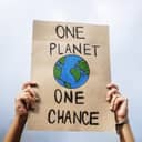 Activist holding up banner 'One Planet One Chance', advocating for environmental action and addressing the global warming crisis.
