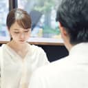 A woman silently looking down with a man sitting opposite her