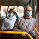 senior man and woman wearing masks while driving on the bus