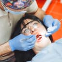 Close-up of a male dentist examining the teeth of a young woman seated in the dentist's chair.