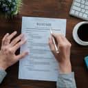 A resume on table being inspected by a person holding a pencil