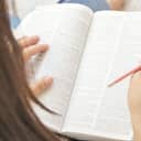 A closeup of a woman holding a dictionary and a pen