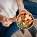 A closeup of a woman eating a meal with fish and vegetables