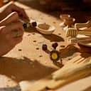 Close-up of a woman using a power graver and grinding machine in her workshop, crafting and carving a wooden spoon.