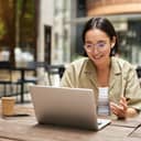 young woman participating in an online meeting from an outdoor café, working remotely while drinking coffee