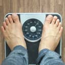A person weighing themselves on a mechanical scale