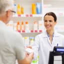 Female pharmacist handing out medicine to patient at pharmacy