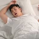 image of a young man snoring while sleeping in bed