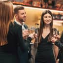 A group of stylishly dressed individuals gather in a restaurant, celebrating a special occasion.