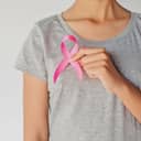 A girl in grey t-shirt holding a pink ribbon across her chest