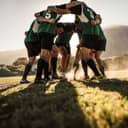rugby team in a huddle, rubbing their feet on the grass and preparing for the game