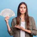 Woman holding lots of cash with a sad expression on her face
