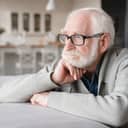 elderly man sitting on the sofa, looking sad and tired at home