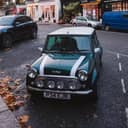 Mini Cooper stationary in a parking lot on the street with shops in the background