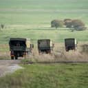 A convoy of military trucks going through green fields