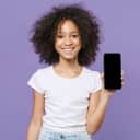 A young girl smiling showing her smartphone against a purple background