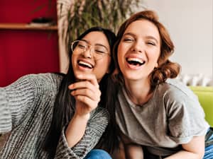 Two smiling friends sitting on a sofa