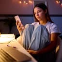 concerned teenage girl scrolling on her phone at night, seated at a desk in her bedroom