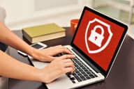 Laptop with a security logo being displayed on the screen used by a person