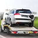 Damaged car on the back of a small truck.