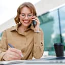 young female office assistant smiling while talking on the phone and doodling