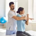 male physiotherapist working on a female patient's injured arm, helping her during rehabilitation therapy