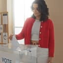 Young woman casting her vote at an indoor polling station during elections.