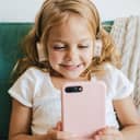 Young girl wearing headphones holding a smartphone.