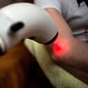 medical worker shining red light on a patient's elbow
