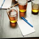 three beer glasses next to a blank sheet of paper and a pen on a table in a pub